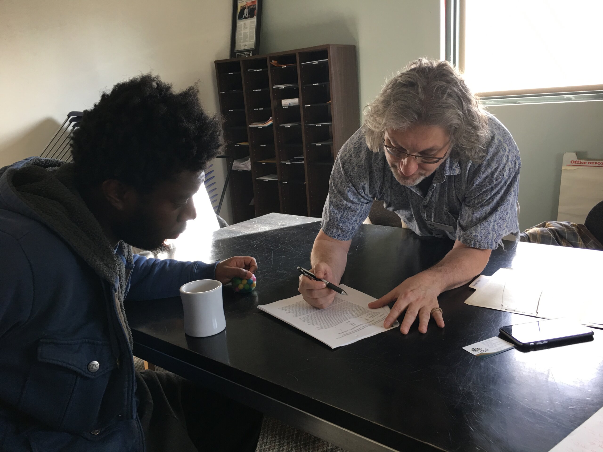 Arnie Swensen, Associate Director of Mission Supports, helps an individual complete paperwork.