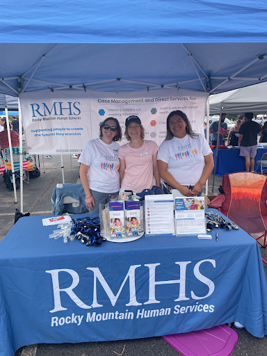 RMHS staff members smiling behind the organization's table at a community outreach event.