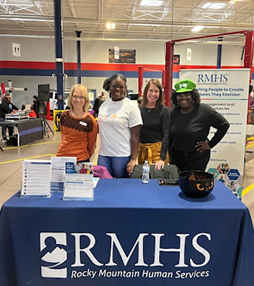 RMHS staff members smiling behind the organization's table at a community outreach event.