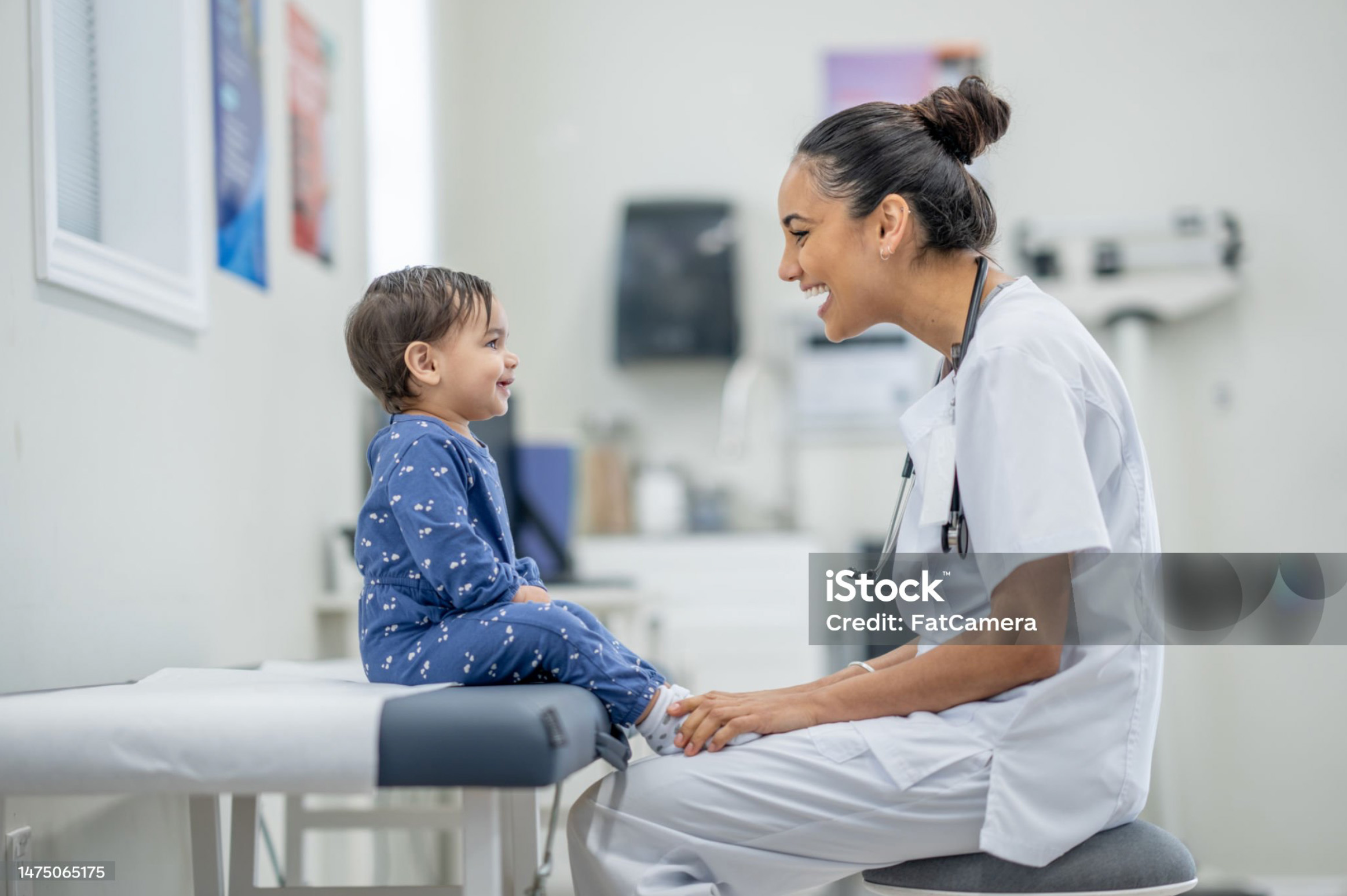 Happy toddler sitting on doctor's table smiling with female medical professional.. Happy toddler sitting on doctor's table smiling with female medical professional..