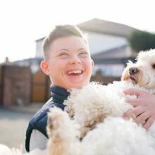 Happy boy with Down Syndrome holding a dog