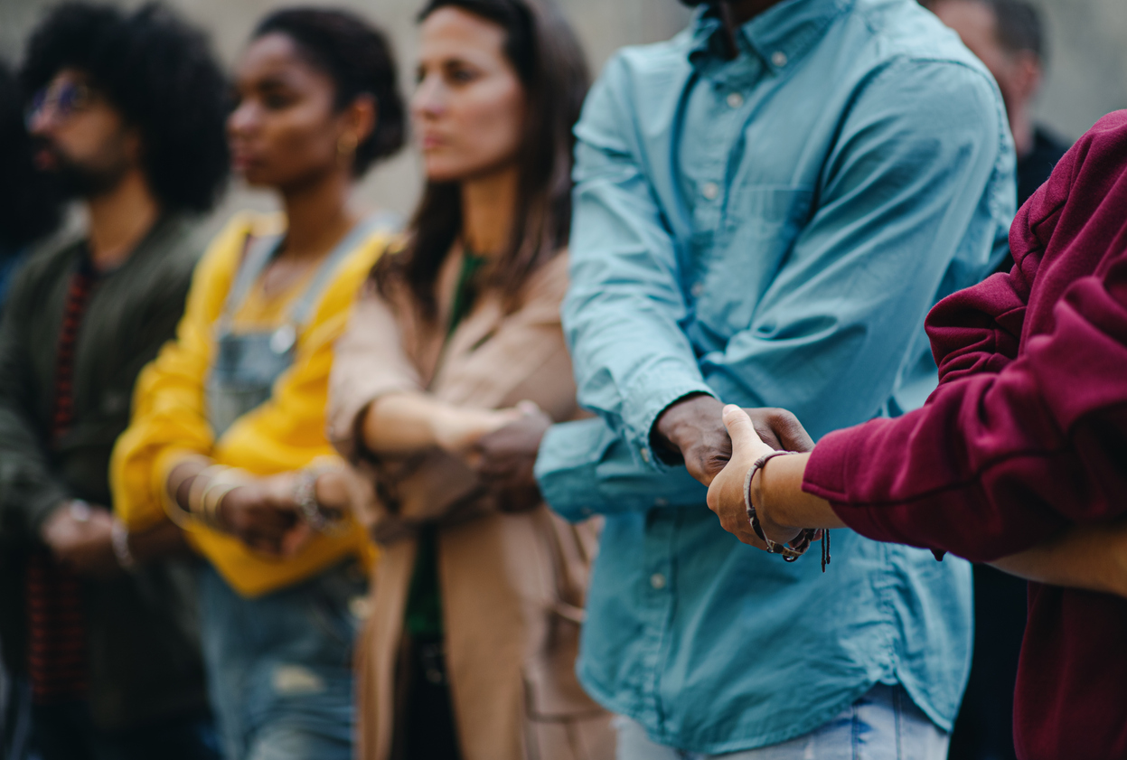 Adults standing in a circle and holding each other's hands in support.