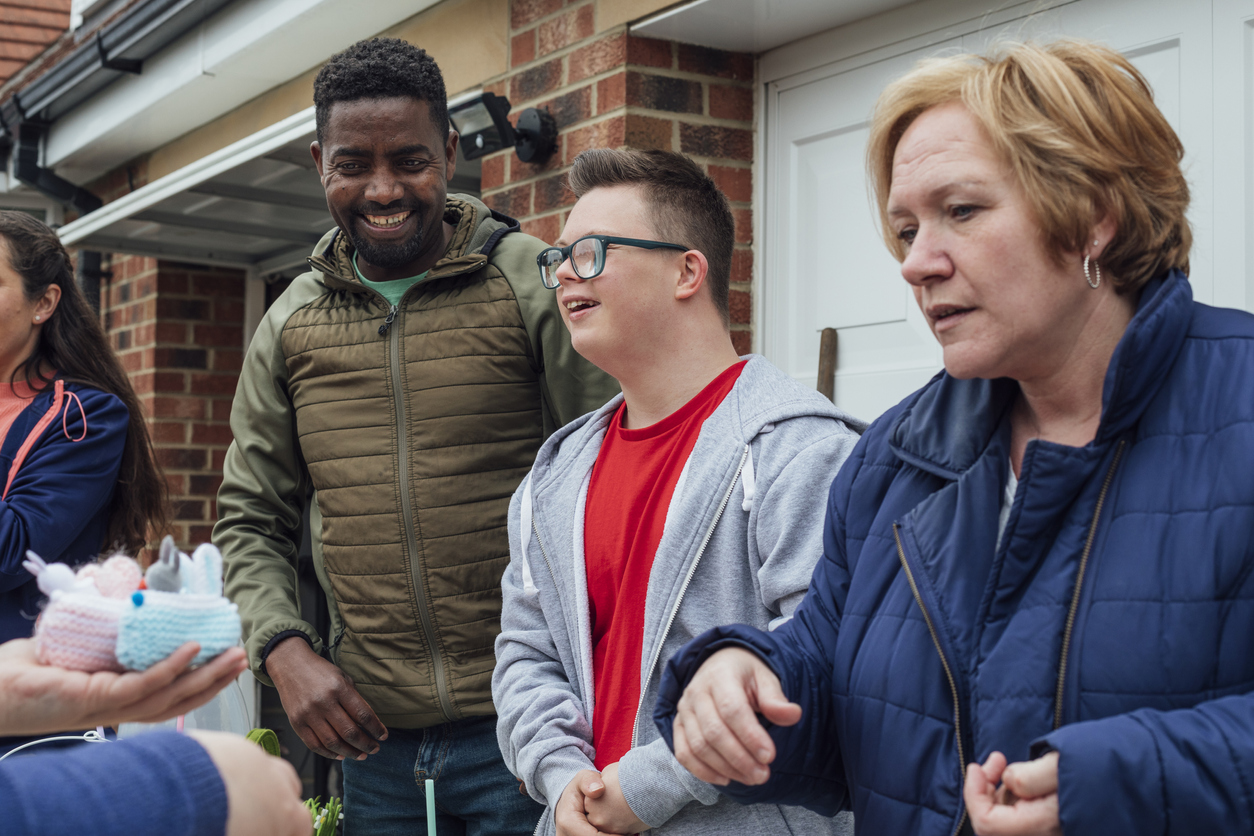 Woman, man, and young adult with Down syndrome at yard sale.