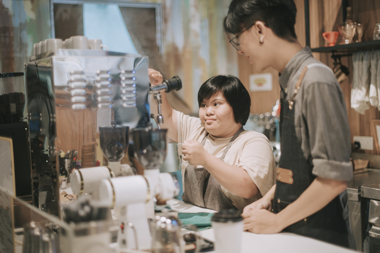 An Asian woman with Down syndrome training as a barista.