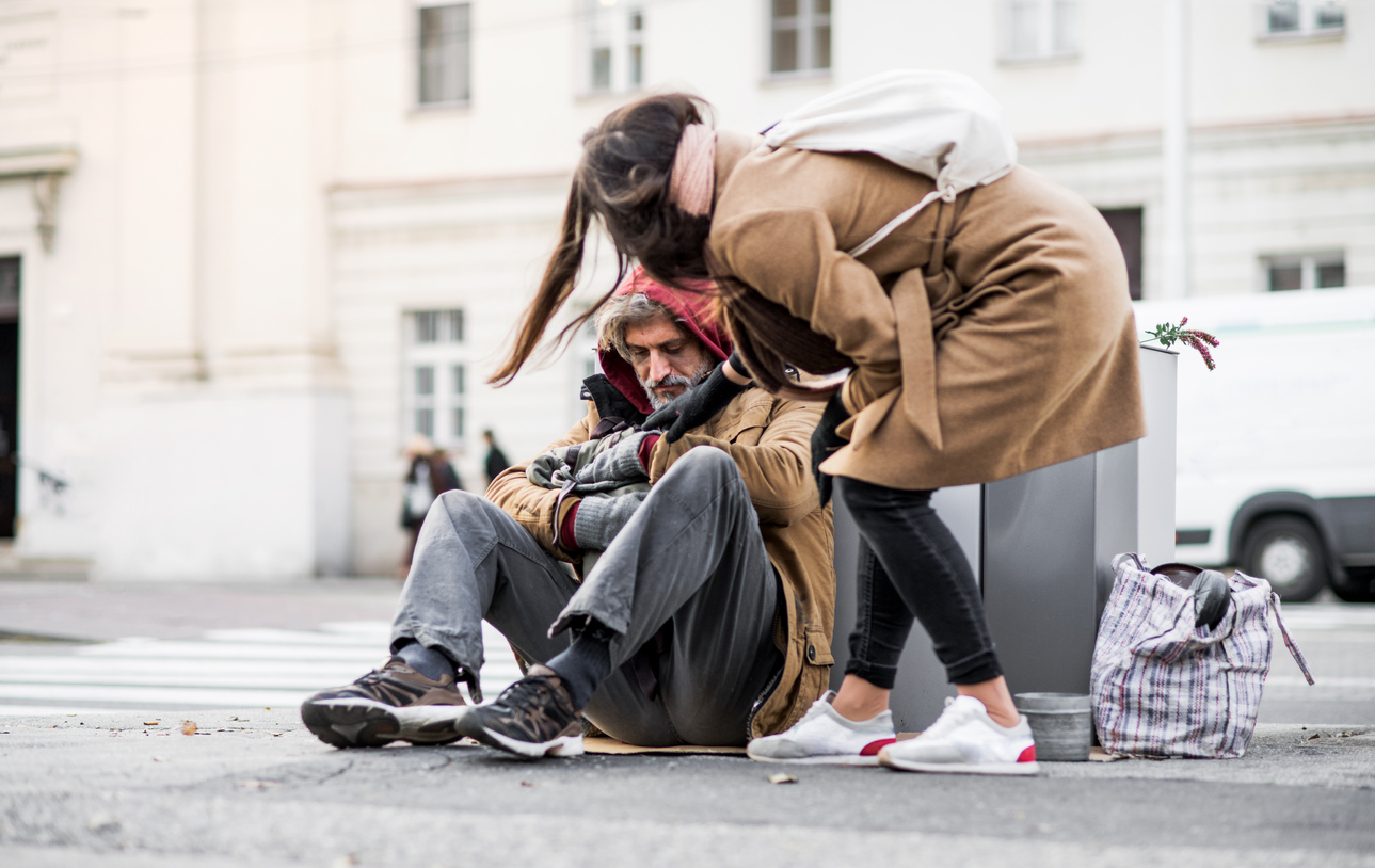 Young woman bending down to support an older man struggling with housing insecurity.