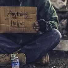 Man struggling with housing instability holding a sign