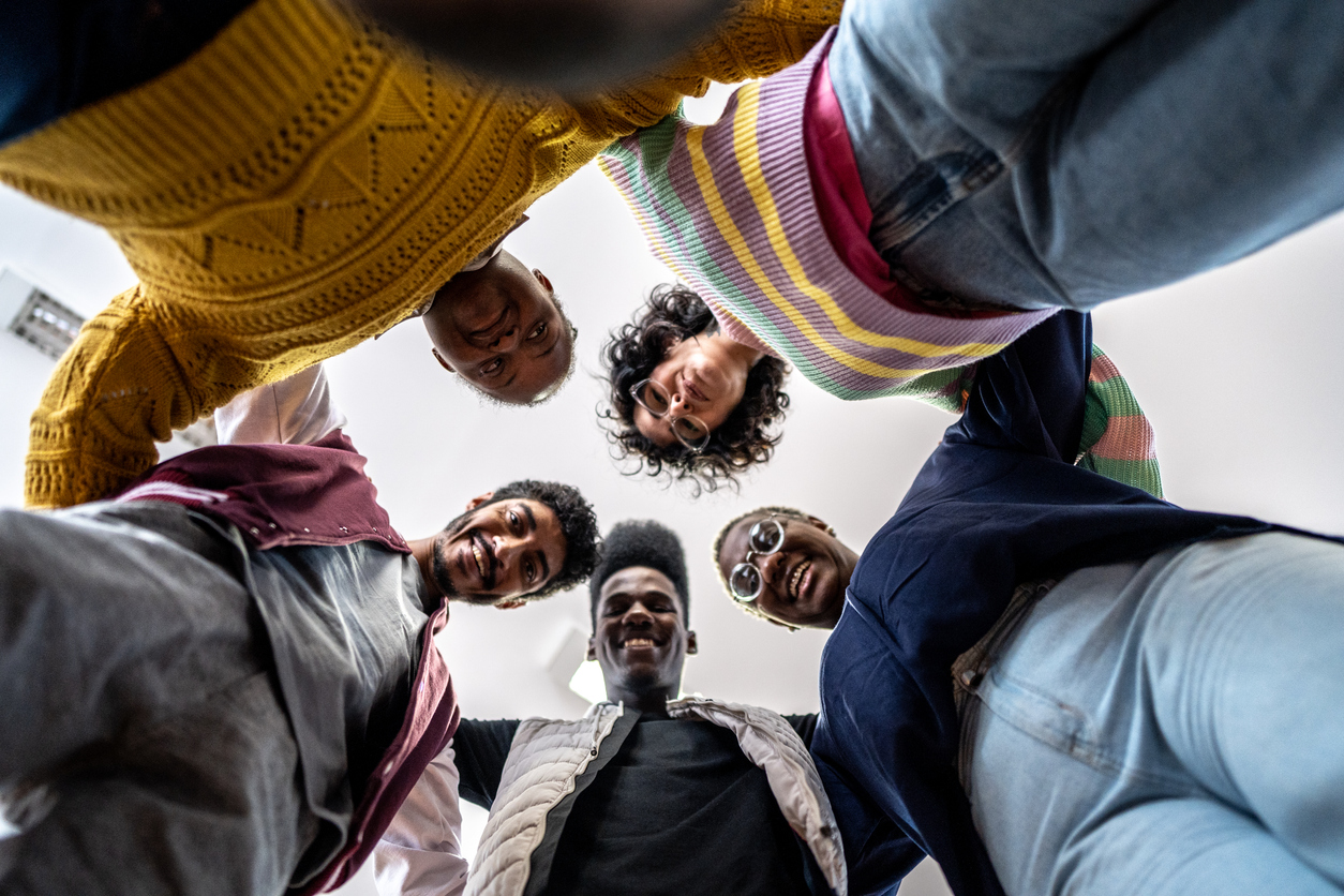 A group of friends huddling above the camera smiling down