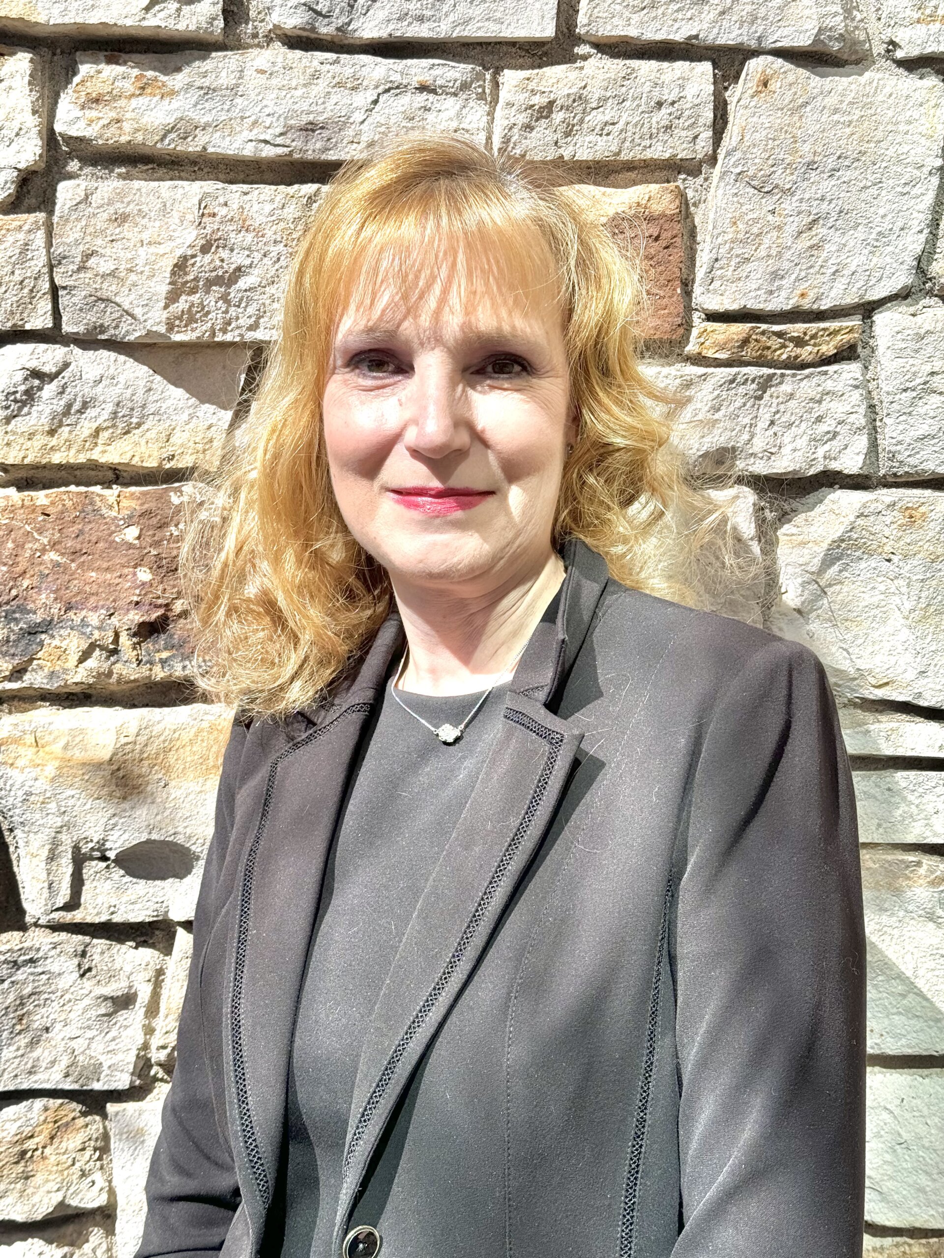 RMHS CFO Nancy Stokes smiling in front of a stone wall.