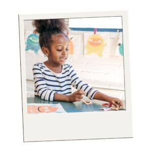 Young girl in a striped shirt plays with letters at a preschool