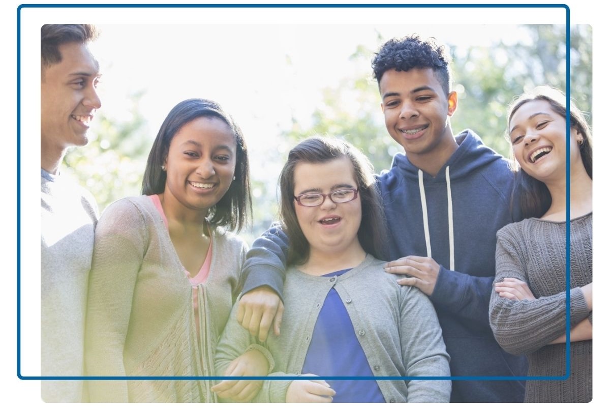 A diverse group of teenage friends stand together, laughing and smiling