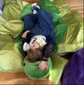 A child lays on the floor on top of a sensory pea pod designed to support with panic attacks