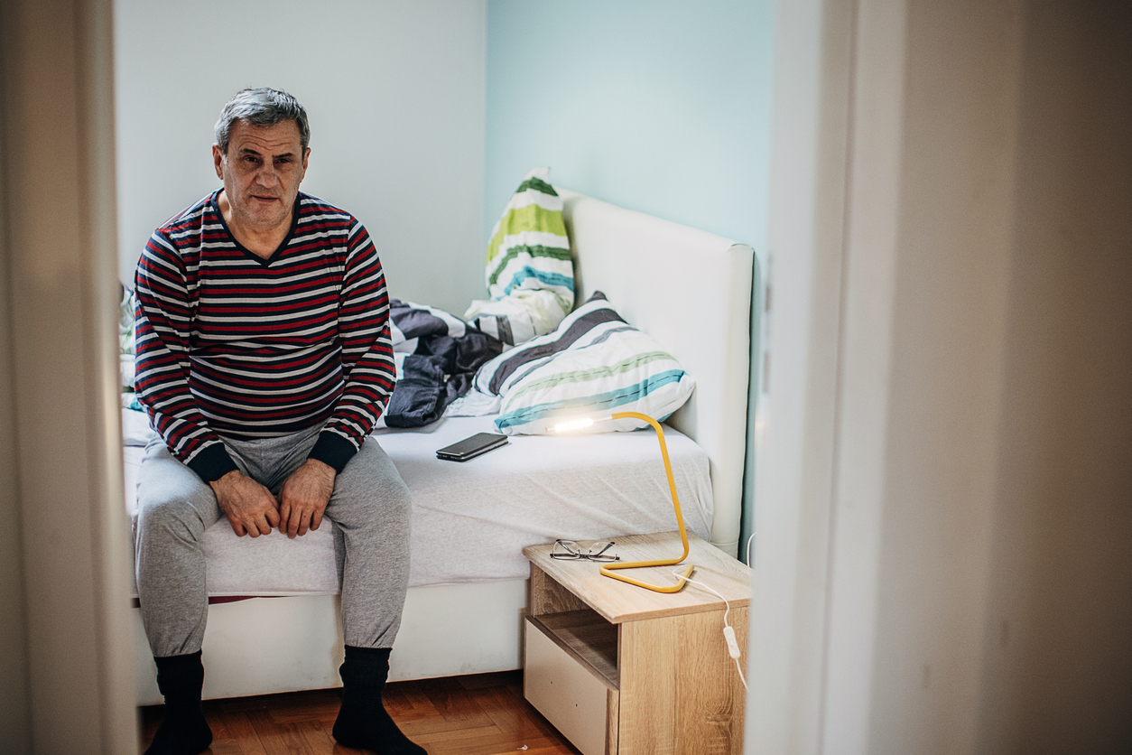 Man sitting on bed in apartment Man sitting on bed in apartment