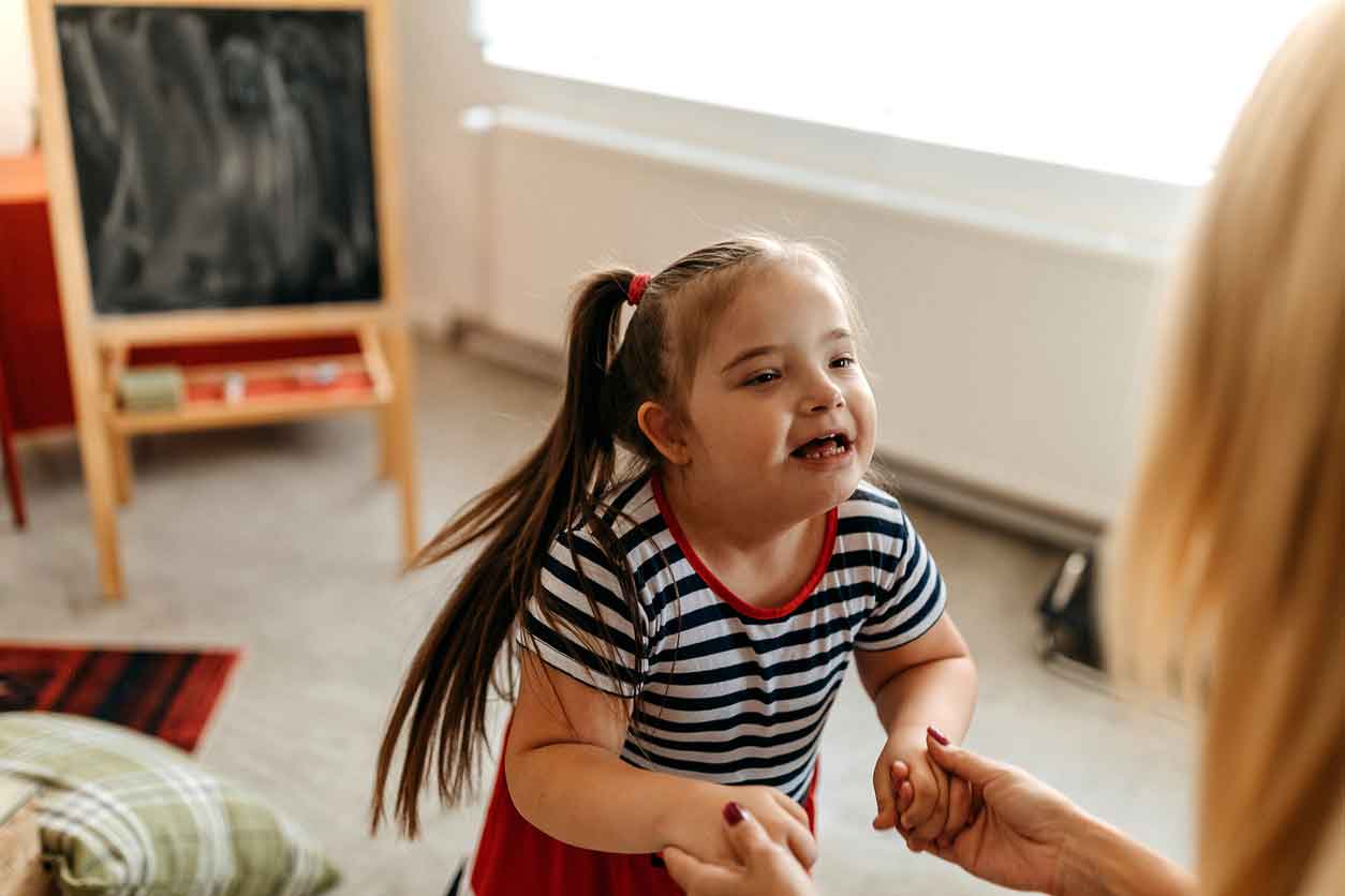 it-takes-two Young girl smiling and holding hands with an adult during an interactive learning session.